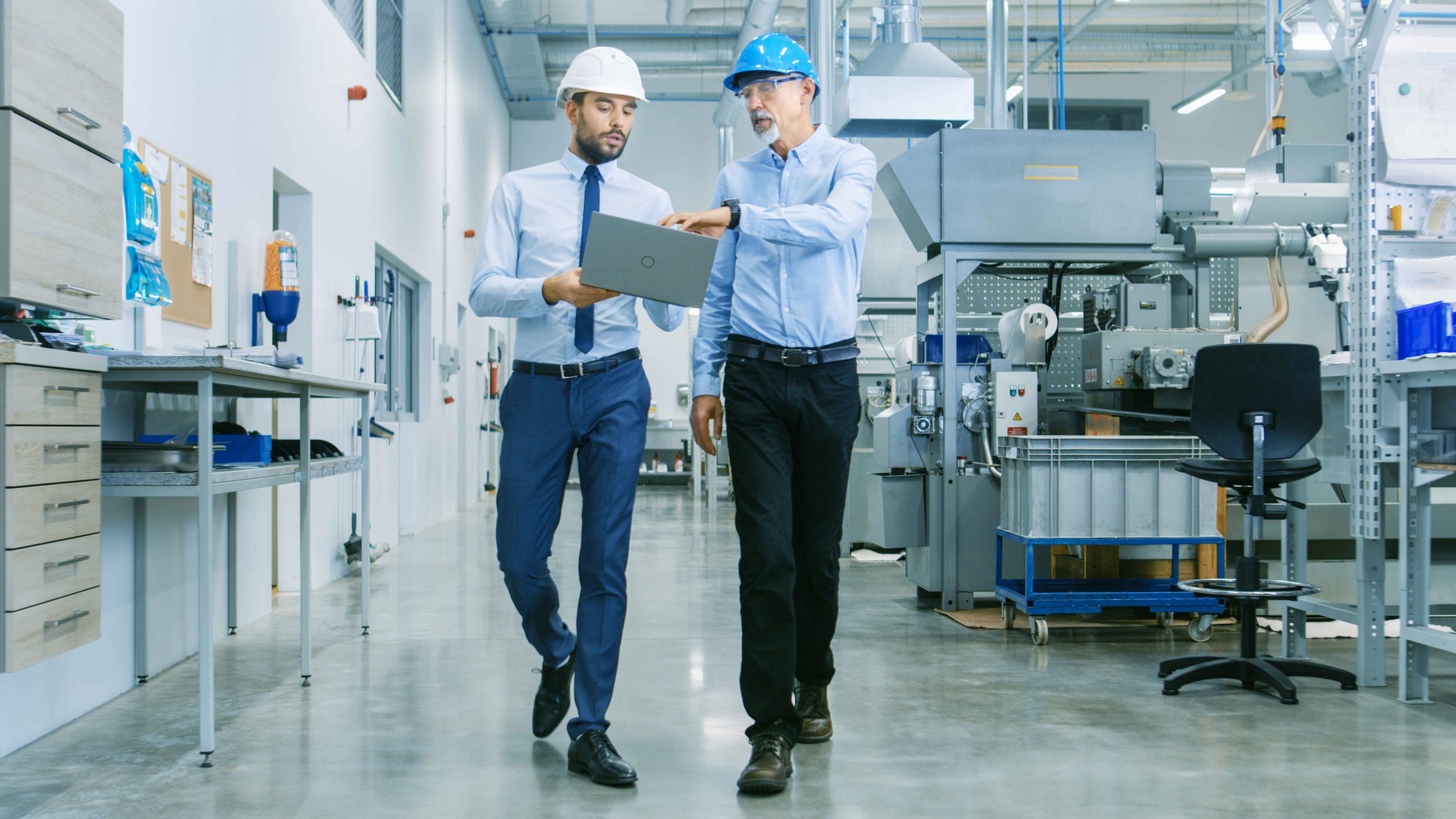 Featured image: Manufacturing managers walking through a worksite - 5S vs. Six Sigma: Which One is Right For Your Organization?