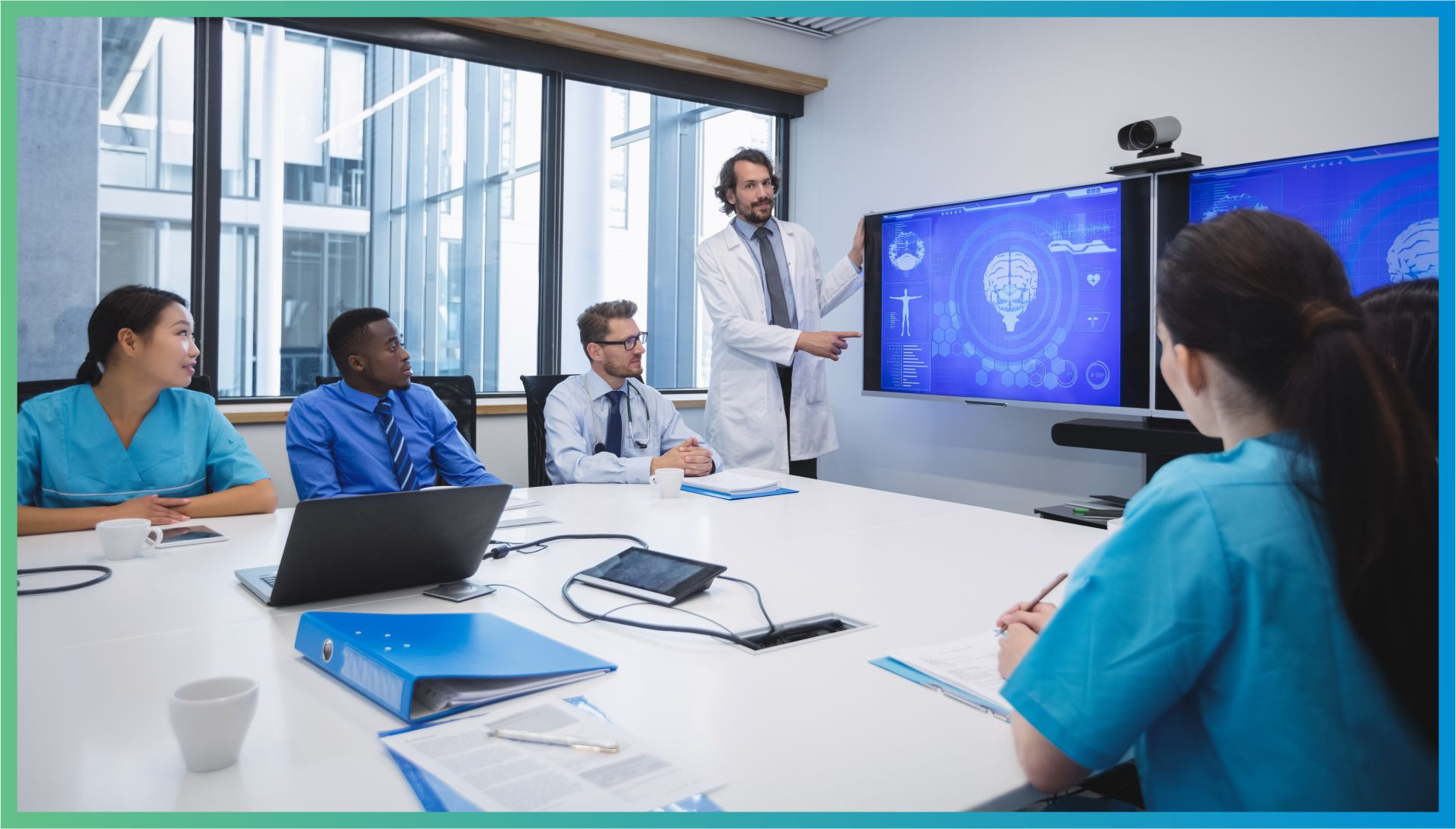 Healthcare team in a conference room reviewing hospital workflow strategies with a doctor presenting on screen